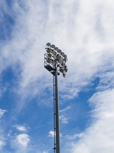High mast stadium lighting pole under a clear blue sky