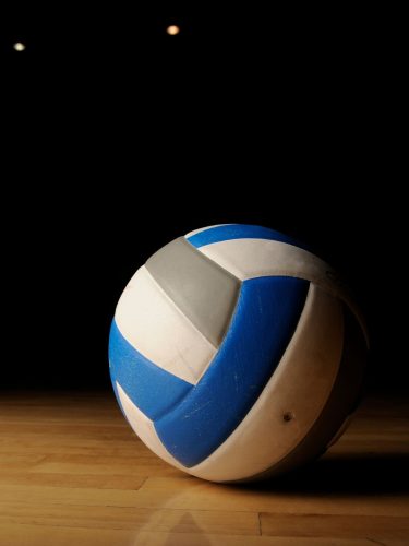 Professional volleyball player spiking the ball over the net